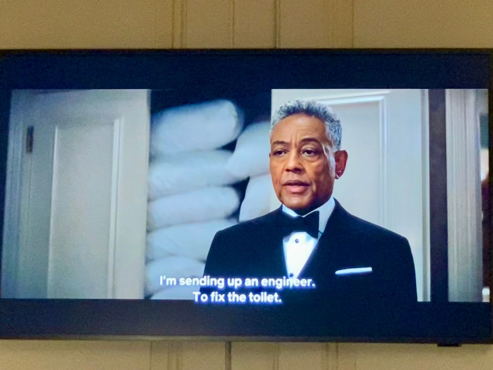 Photo of a TV showing an episode from the show “The Residence” showing Giancarlo Esposito stating: “I’m sending up an engineer to fix the toilet”