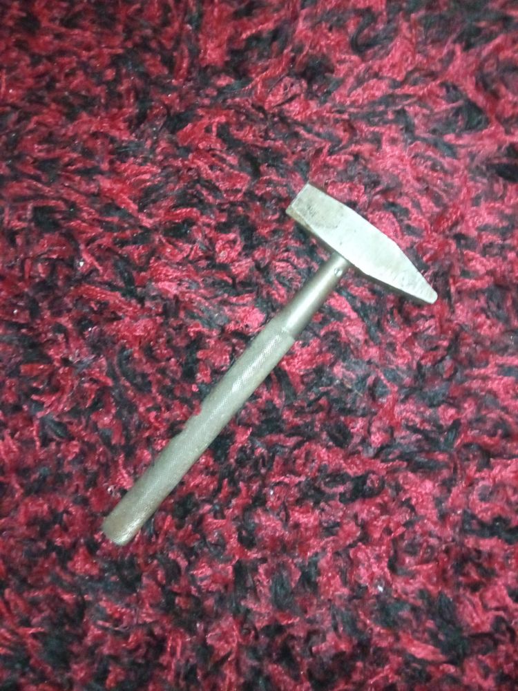 Picture of a full steel hammer (with steel handle) on a red carpet.