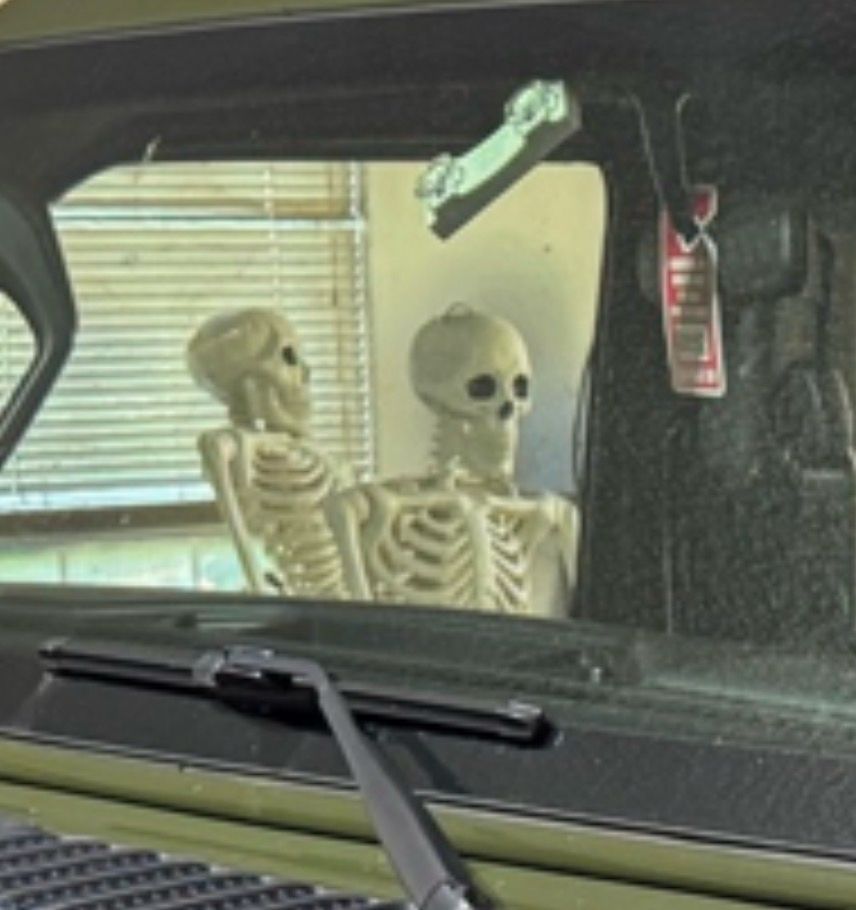 inset of the photo above showing a Halloween skeleton through the window of the jeep