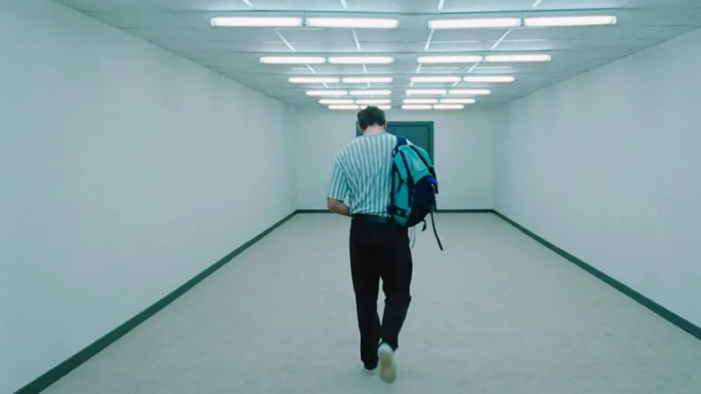 A shot from Charlotte Wells’ Aftersun (2022) Paul Mescal as Calum walks away from the camera down a bare hallway towards a green door from which he can’t come back
