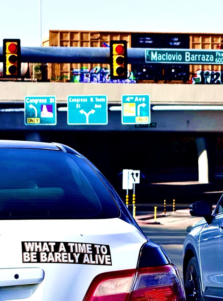 Car with bumper sticker “what a time to be barely alive”