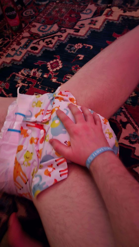 Daddy came home and wanted to grope my napppy...same outfit as before but now I'm lying on the carpet with his hand on my diaper.

The band on his wrist is a funny story...it says I ❤️ diapers. He doesn't take it off. I was on Daddying duty on a night out and put it on him because he kept trying to buy me drinks and I was insistent on paying...so I made him wear it and said "You don't take this off till I tell you to and you don't buy drinks for me while you wear it." Months later I still never told him to take it off 😊