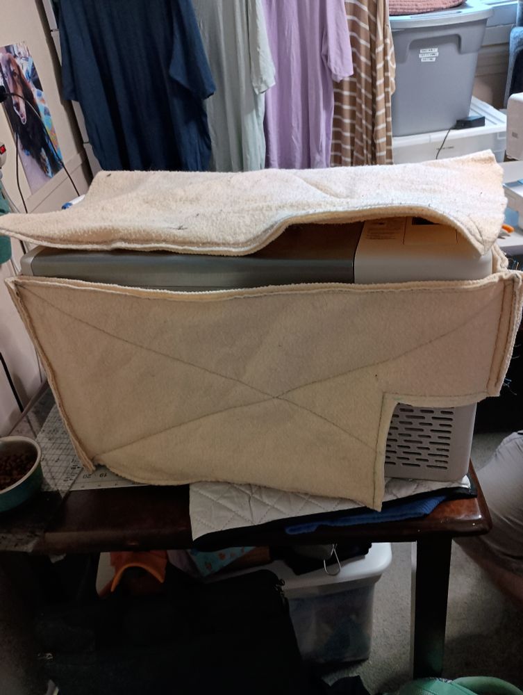 A handmade cover for a 12 volt cooler. The cover is roughly cut out of an old blanket.