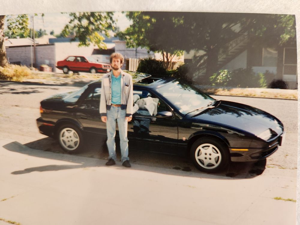 My dad standing in front of his brand new 1993 Saturn, looking like he doesn't want to pose for this photo