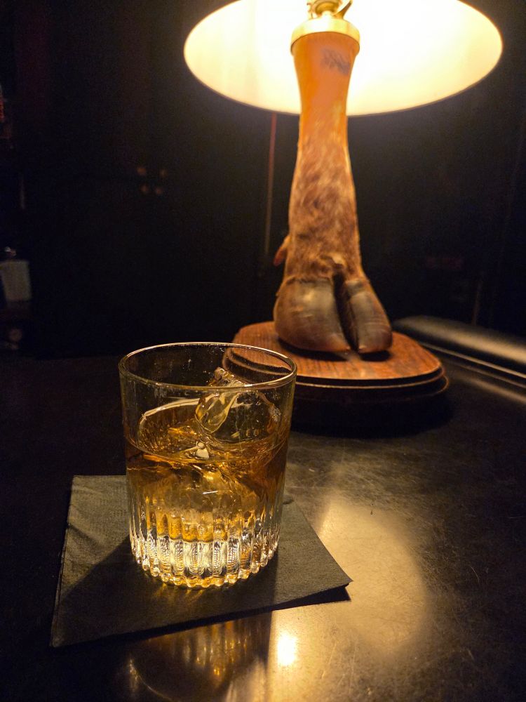Rocks cocktail at a bar with a clover hoof lamp behind