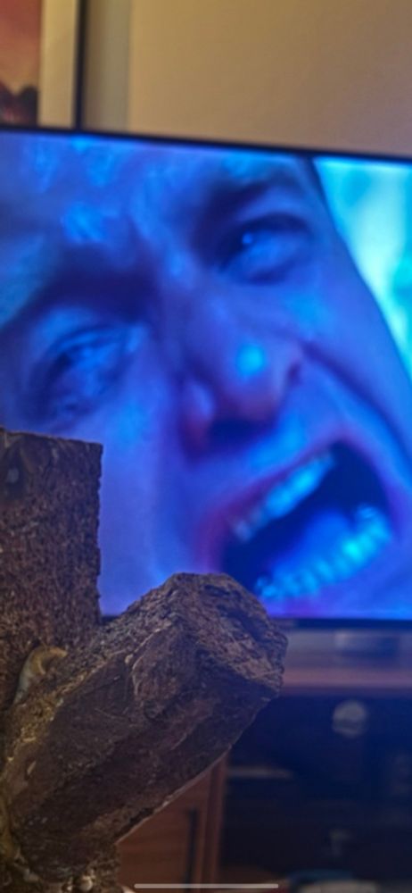 Closeup of an unknown movie/show on a TV of a man screaming or something in blue light 