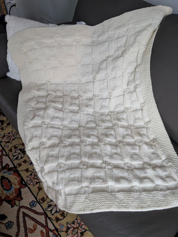 Hand knit ivory blanket in a reversible box pattern. I have no idea of the measurements as that would mean I knew what I was doing. 