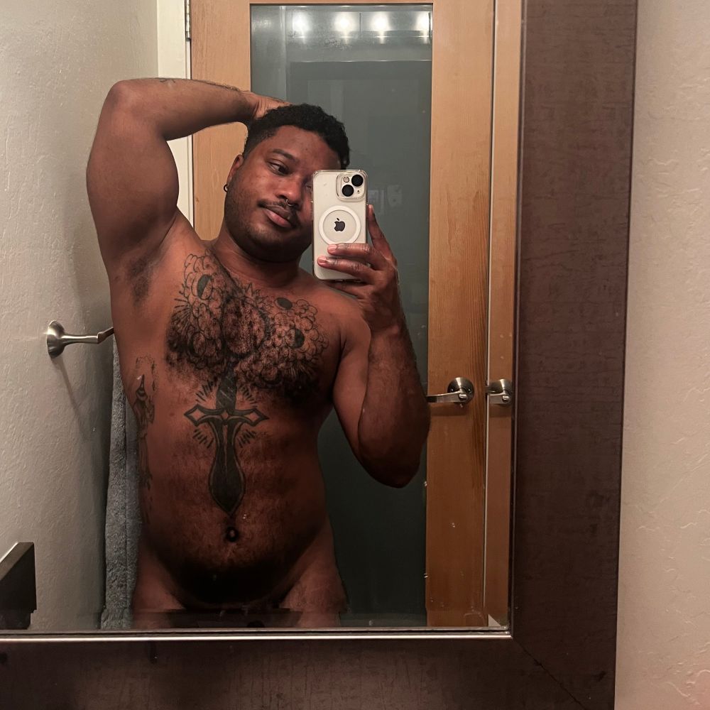 A mirror selfie of a naked CJ lightly flexing with an armpit raised.