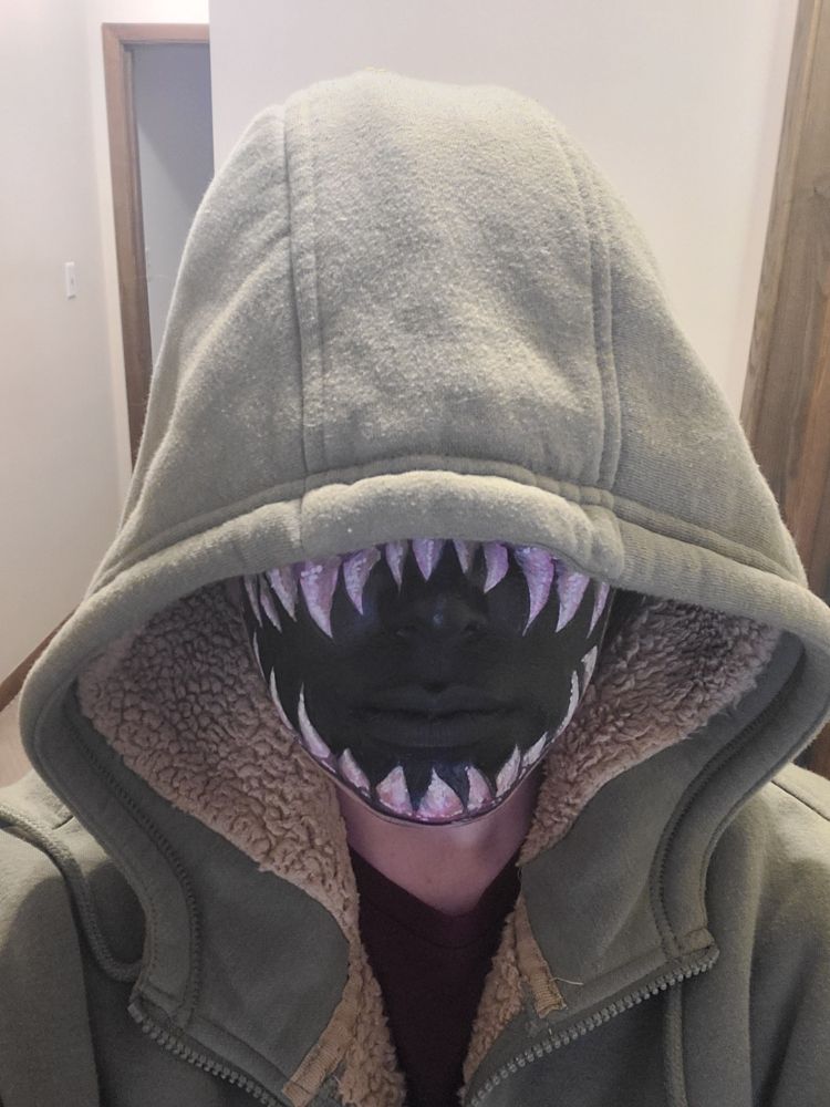 LoS's face, covered in a ton of facepaint so it looks like a wide, toothy maw. Actually features are nearly impossible to distinguish. Her eyes are covered by an oversized hoodie hood