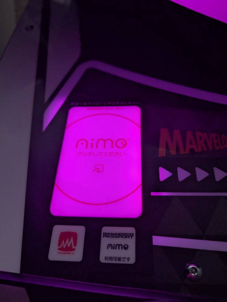 The card reader on the arcade game WACCA, lit up with pink lights as a demonstration.