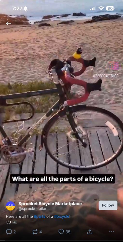 screenshot of a video playing in the bluesky app. it shows a still of a bicycle standing on a boardwalk near a beach with the caption "What are all the parts of a bicycle?"