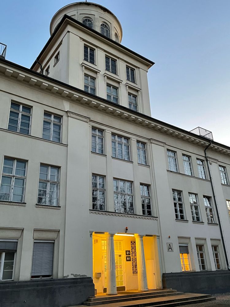 Schulgebäude mit beeuchtetem Eingang.