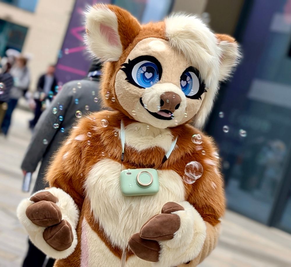 A brown and cream deer fursuit with bubbles floating around it.