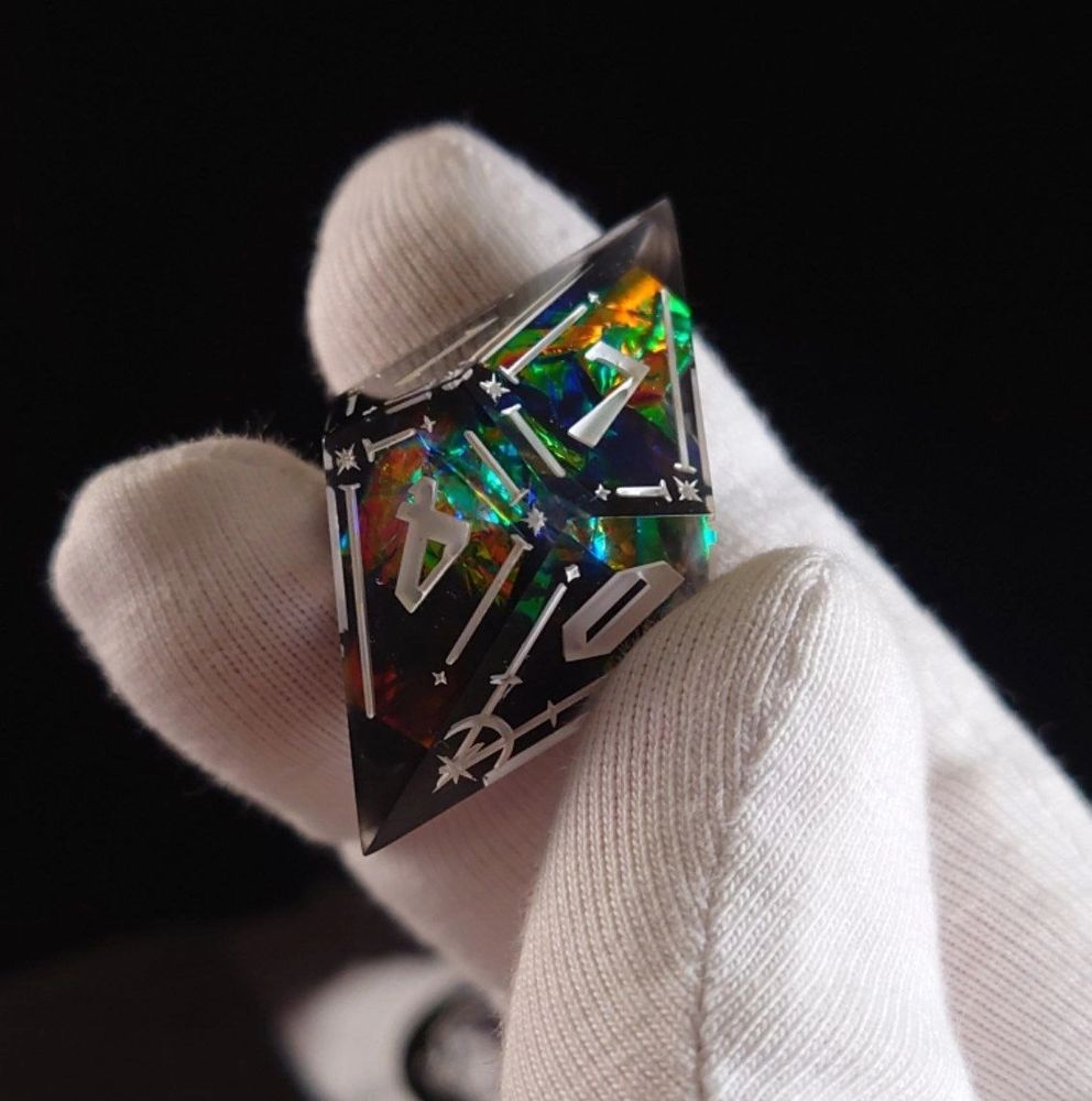 a black ten-sided die with holographic film and white numbers