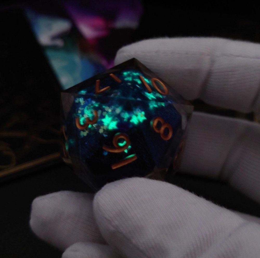 a blue d20 with a liquid core and golden numbers that glows in the dark