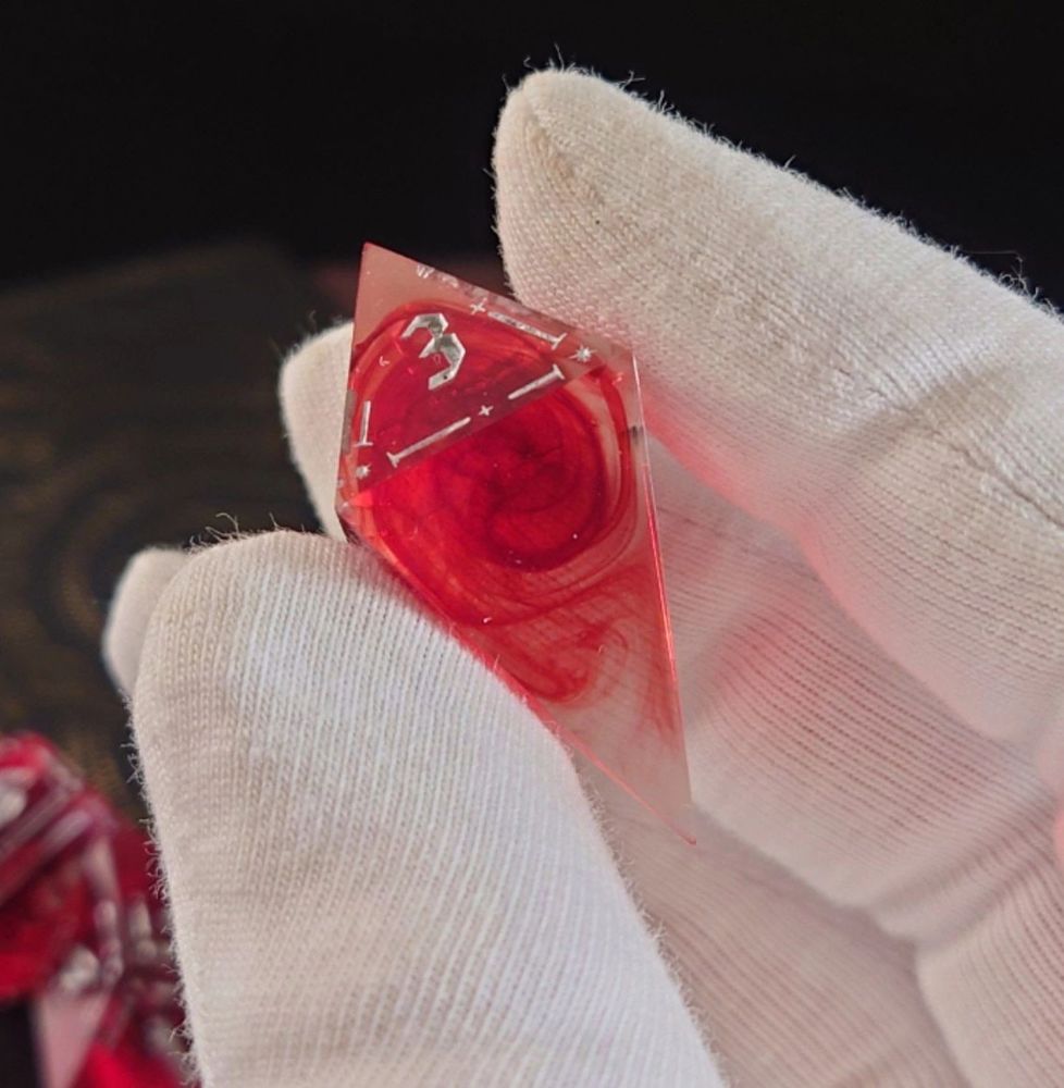 a red four-sided dice with splotches that looks like blood