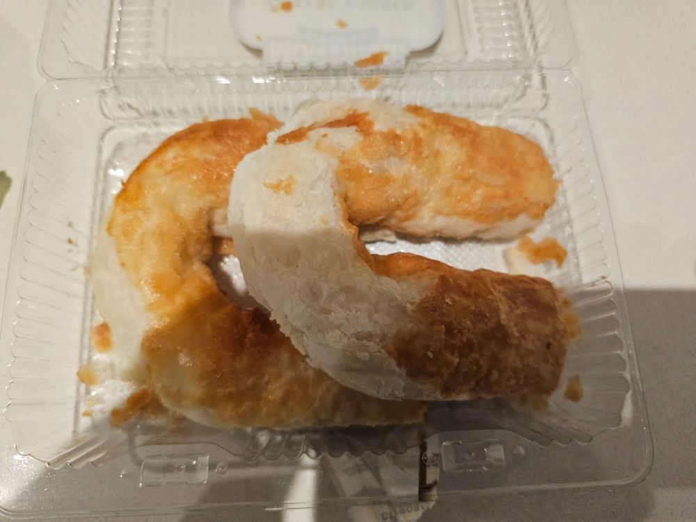 The open clamshell showing two flaky horseshoe shaped pastries 