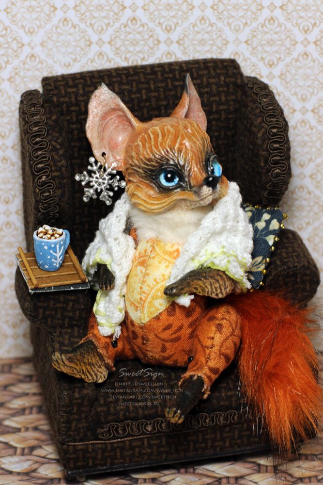 An original fantasy art doll by Svetlana Polupanova (SweetSign), a red fox with blue eyes and a snowflake earrings relaxing in an old armchair with a cup of hot chocolate 