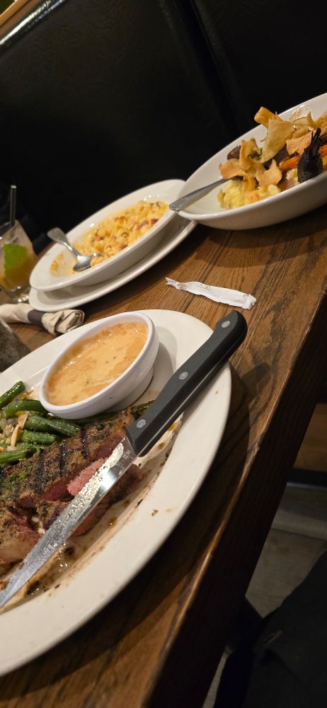 Steak with green beans , short ribs and potatoes , and Mac and cheese on a table in a restaurant. Yum. 