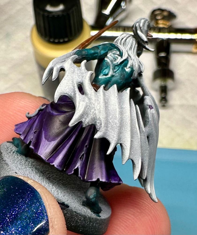 A mandrake with teal skin and purple skirt.