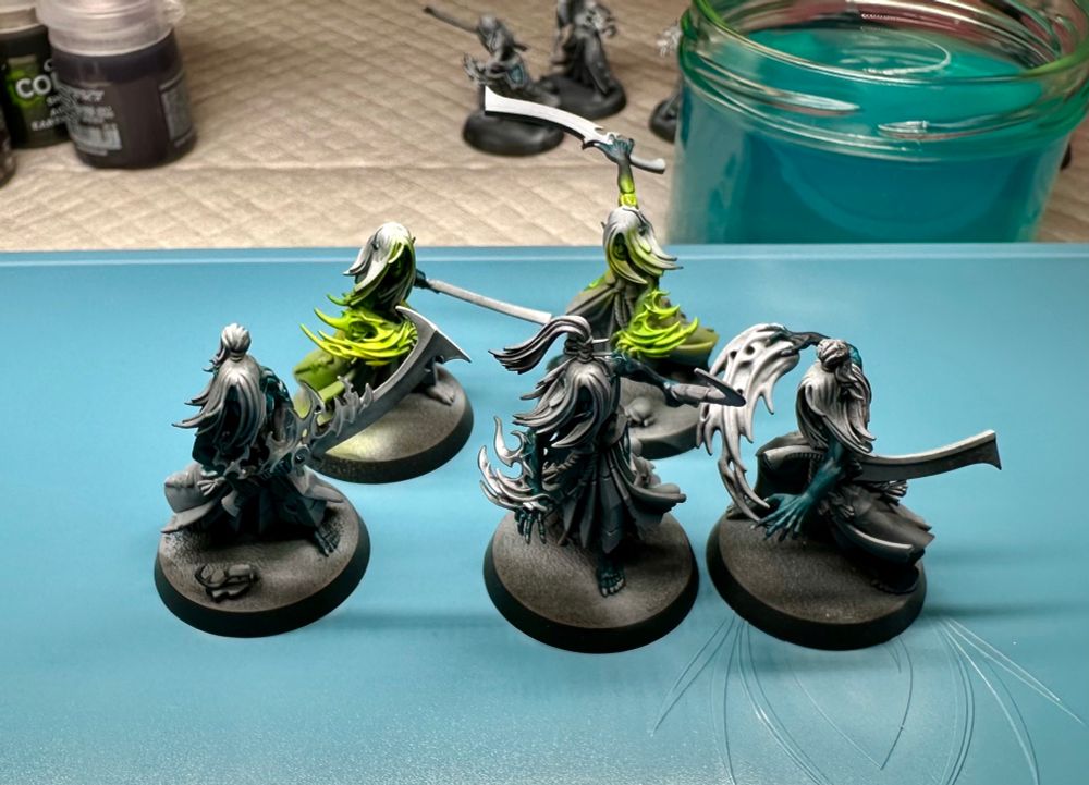 5 mandrakes with their skin base coated, two show green flames painted with a glowy gradient.