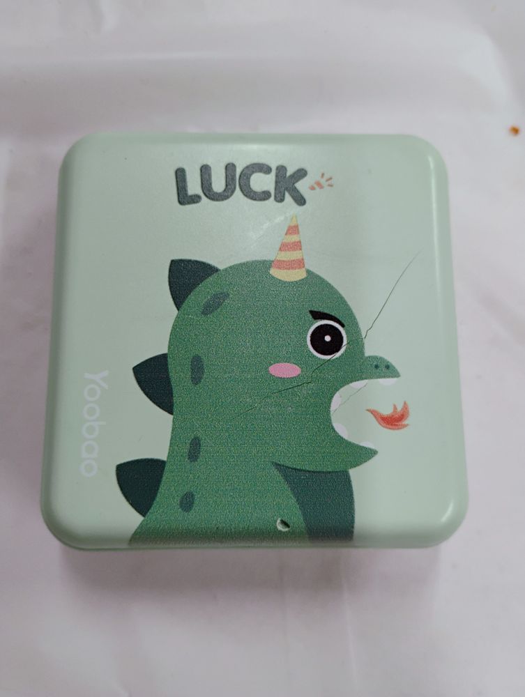 picture of a portable battery charger. there is an image of a chibi dragon breathing fire printed on it, with the word luck above his head. there are cracks in the charger indicating the battery inside is expanding.