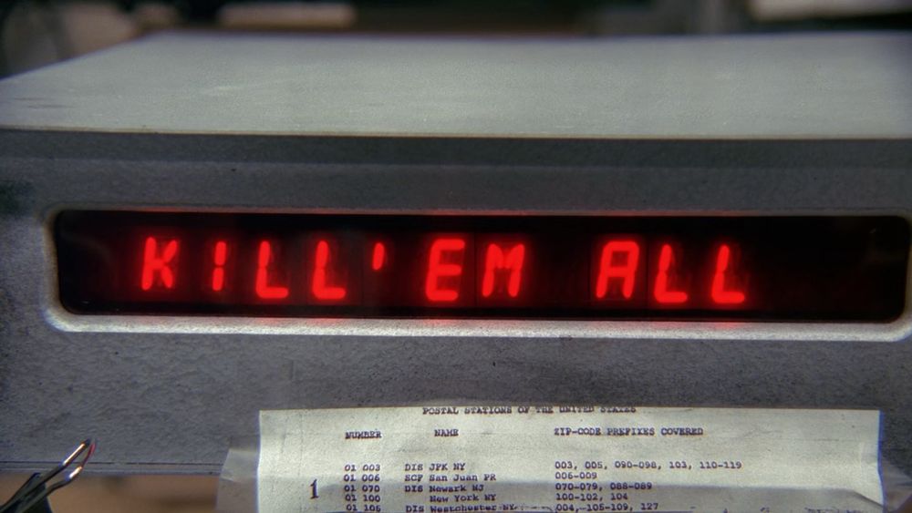 Screenshot from an X Files episode. It is an LCD display that says “Kill em all”. 