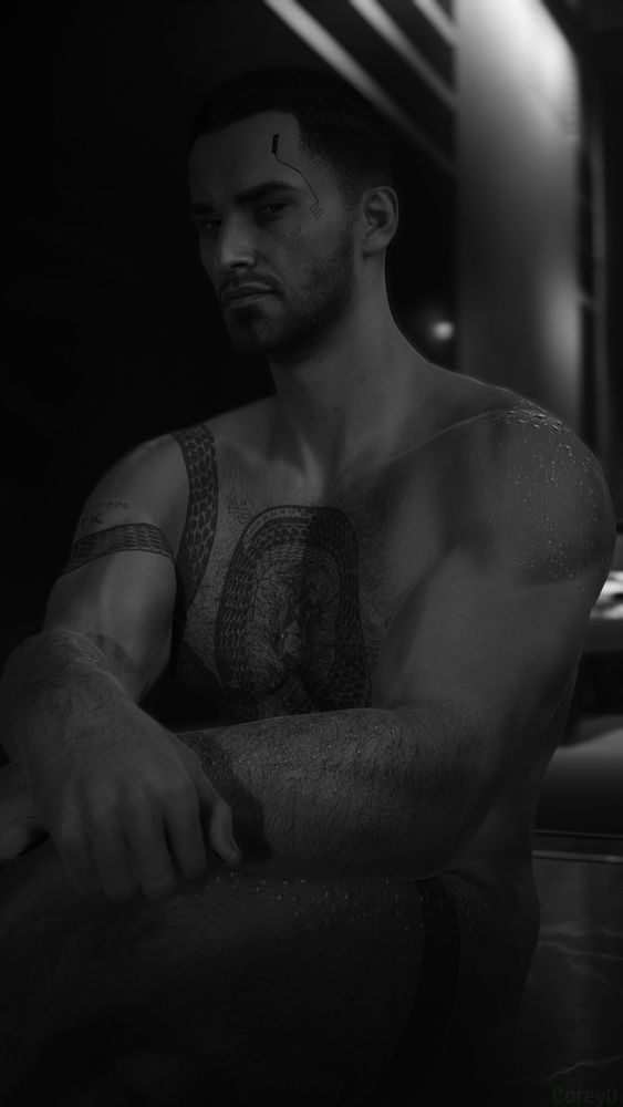 Black and white picture of Corey V wearing nothing but water droplets, sitting on the floor and staring into the camera. 