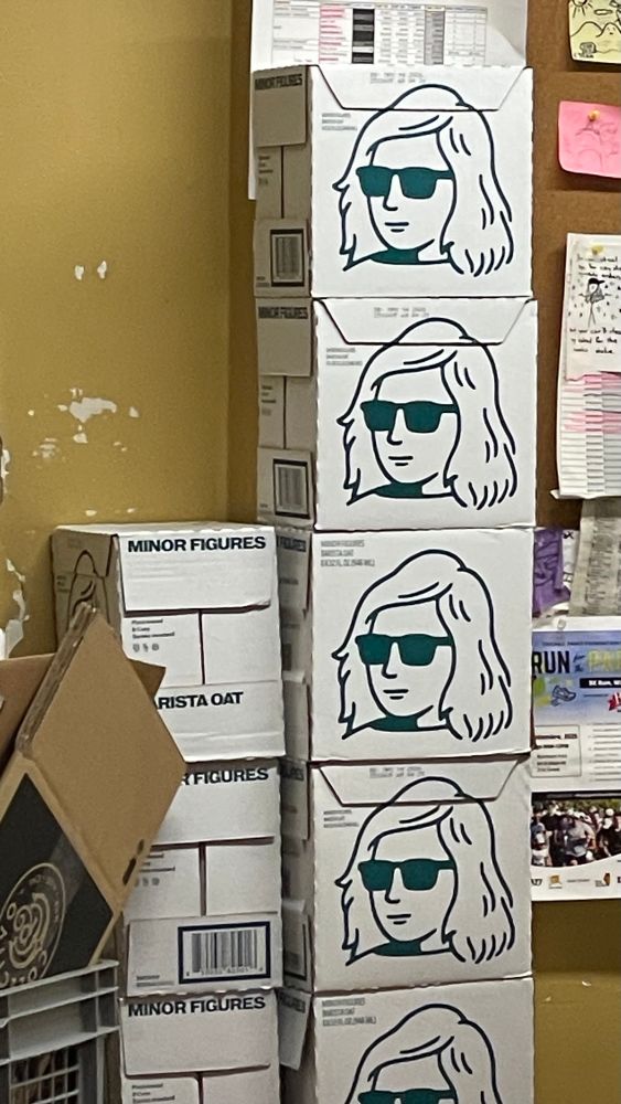 A stack of cardboard boxes, each with a simple drawing of a woman’s face wearing sunglasses 