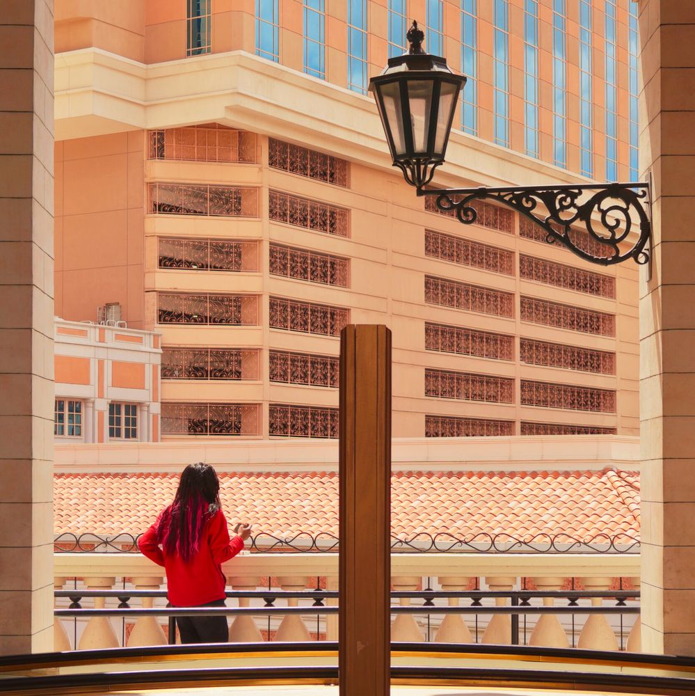 Woman holds a cell phone in an arch way near escalators overlooking the skyscrapers of Sands Blvd on the Vegas strip.