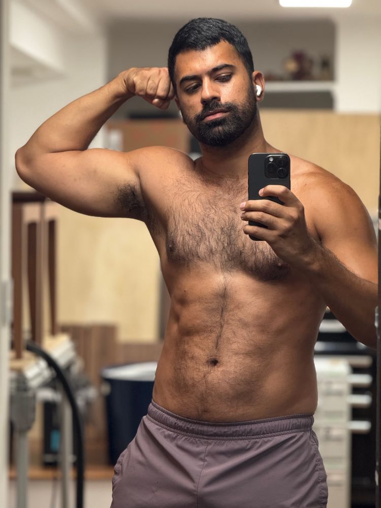 shirtless mirror gym pic wearing purple gym shorts while flexing my bicep and abs 