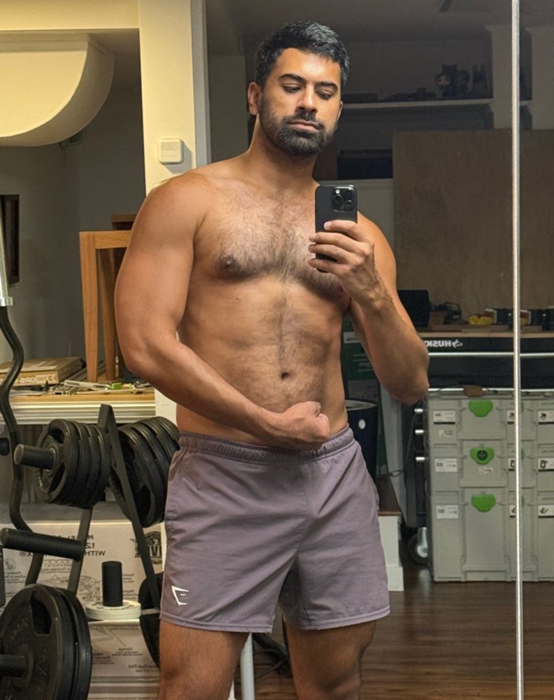 shirtless mirror pic wearing purple gymshark shorts while flexing my arm with a tricep pump