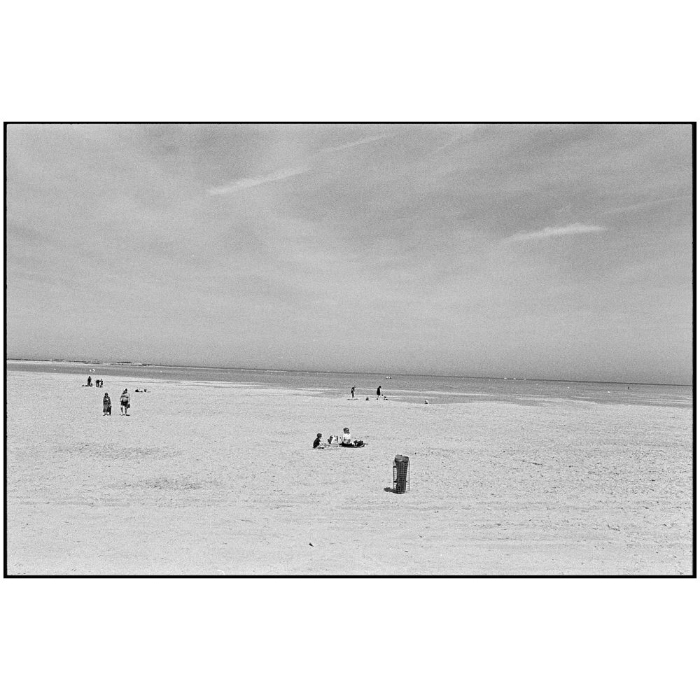 sehr breiter heller Sandstrand am Ärmelkanal, blauer Himmel mit Schleierwolken, am Strand verteilt paar Spaziergänger