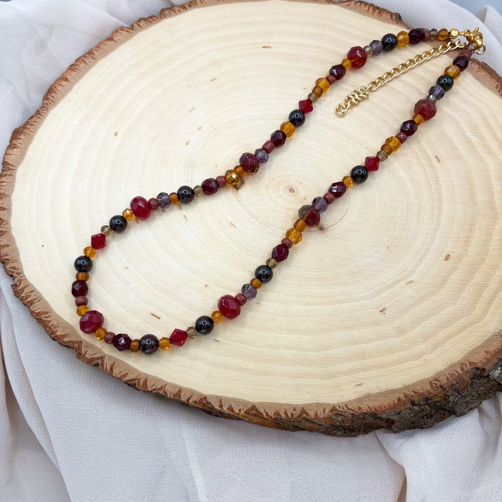 A beaded necklace with red, maroon, and orange beads 