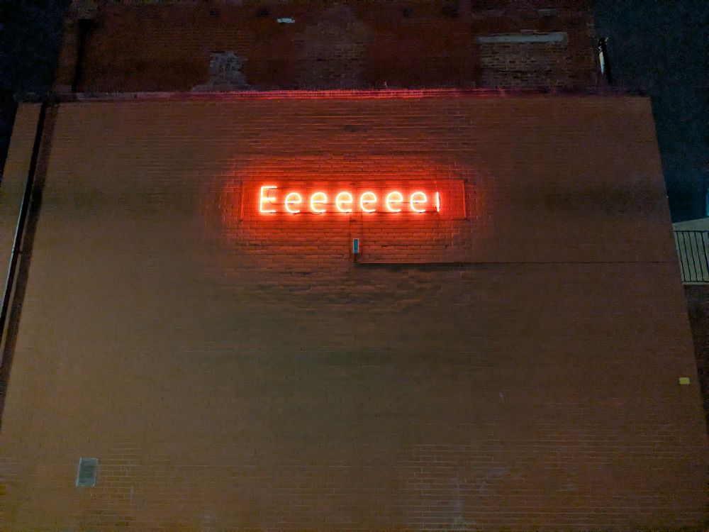 A red neon 'Eeeeeee!' sign on the side of a building
