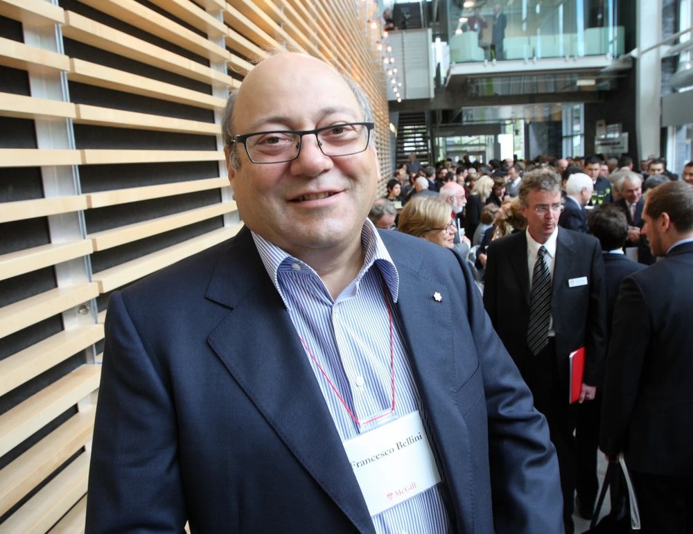 Francesco Bellini smiling at a McGill University event, with attendees in the background inside a modern building.