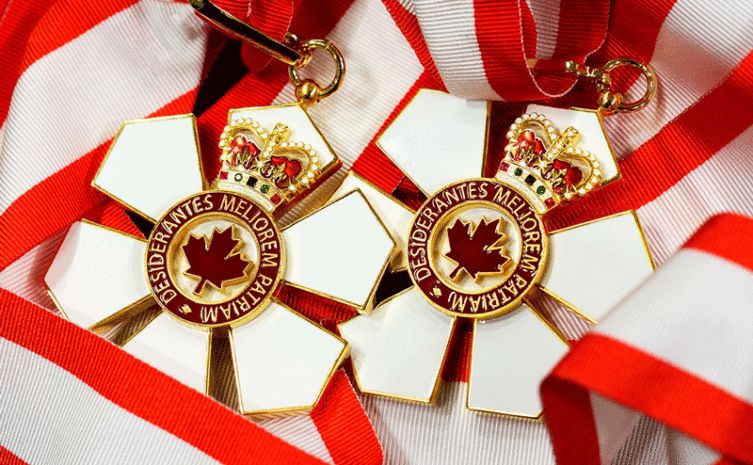 Two Order of Canada medals with red and white ribbons and a gold maple leaf.