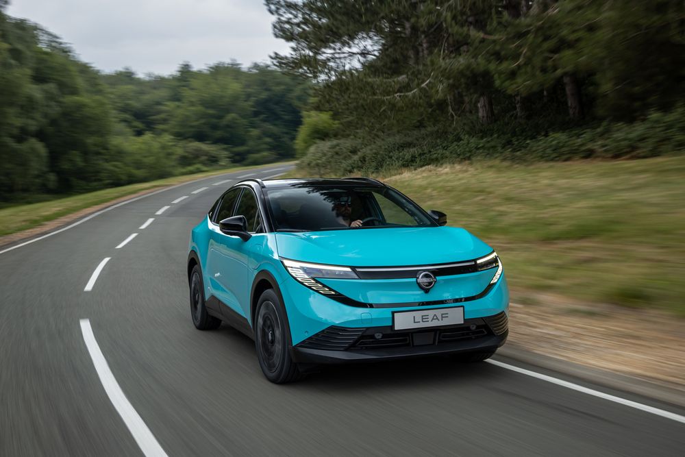 A left hand drive, third generation Nissan LEAF taking a bend on the wrong side of the road.