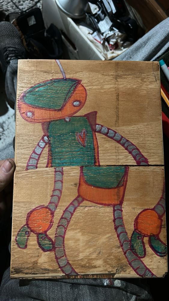 Whimsical cairobot bean and tube style robot, split in half at the midsection by a crack in the wood panel it is painted on. 