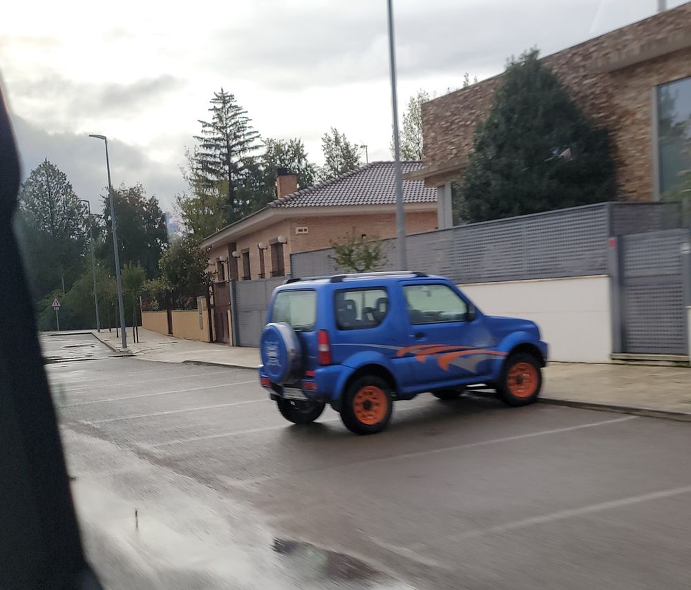 A blue Suzuki Jimny with red accents 