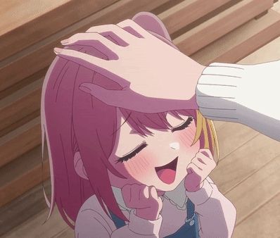 a girl with pink hair is being patted on the forehead by a person