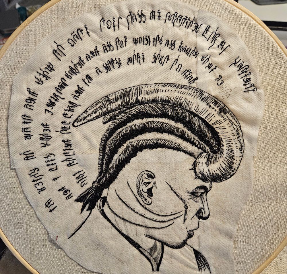 Nearly-finished embroidered portrait of Wyll Ravengard from Baldur’s Gate 3 with a halo of infernal script ringing his head
