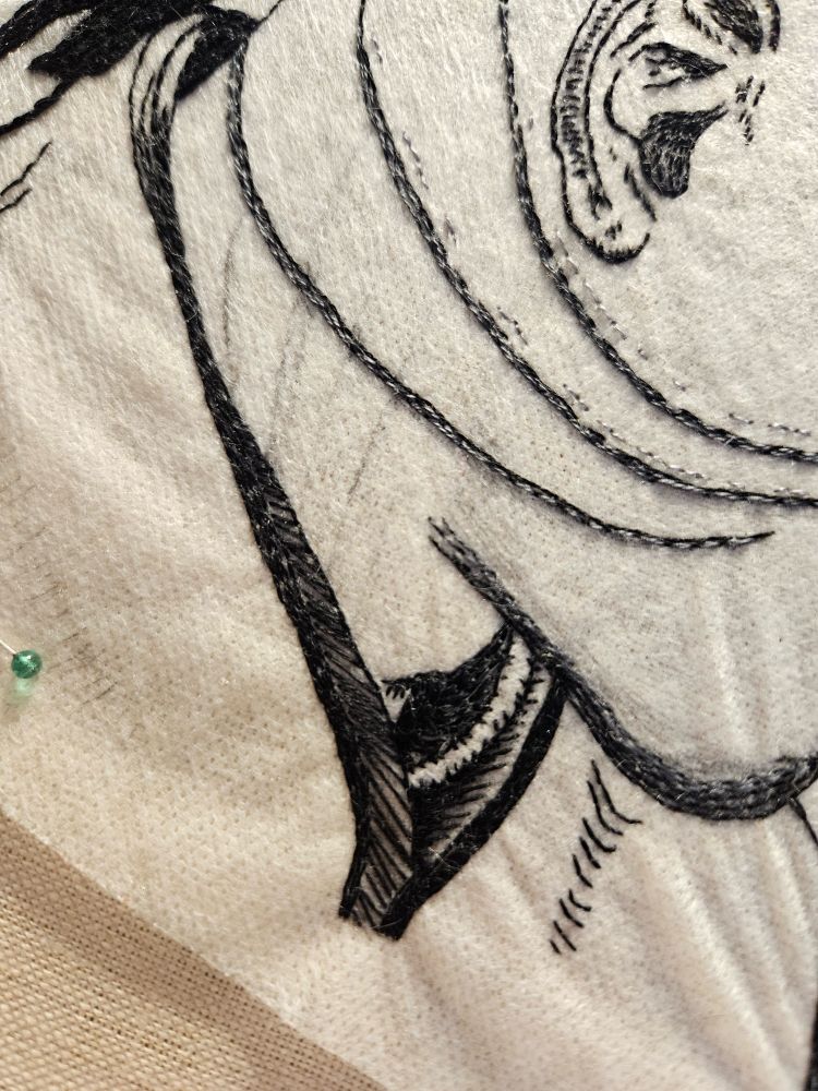 Close-up photo of the most recently finished portion of the embroidery showing the different textures of his shirt collar.