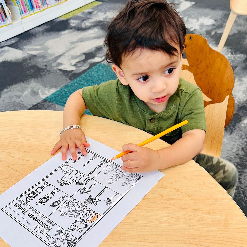 A little boy coloring a sheet of paper.