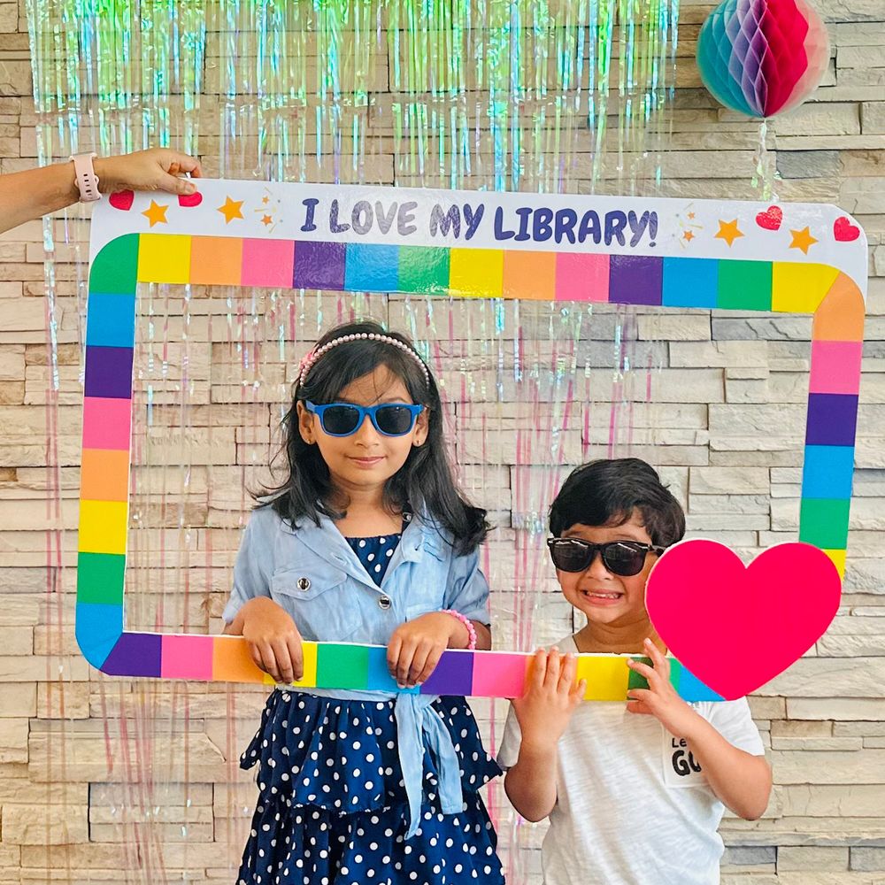 Two kids pose with a frame that says I love my library!