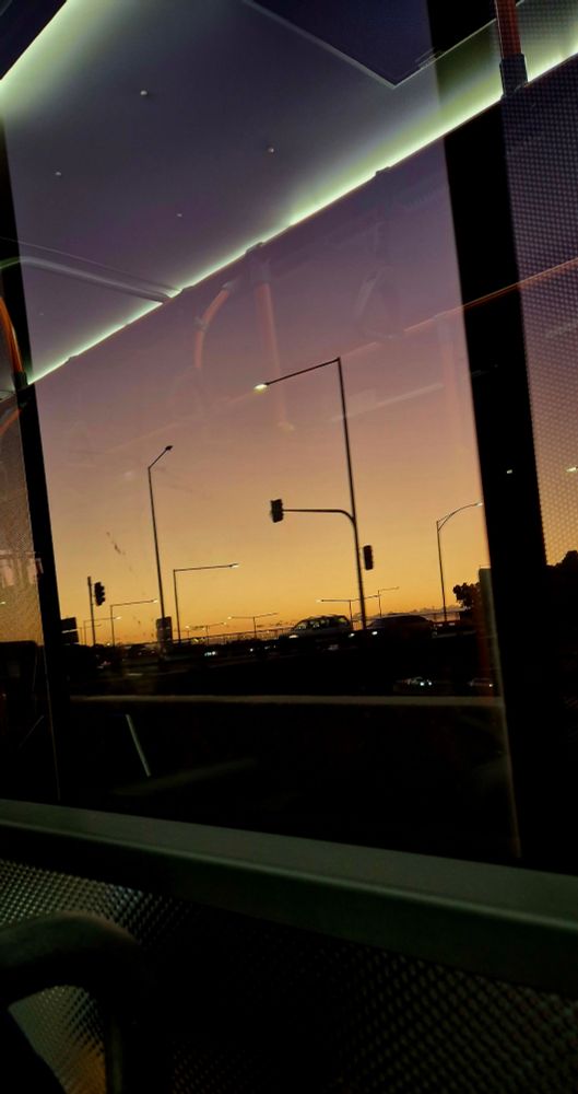A sunset as seen from through a bus window whilst travelling on the motorway