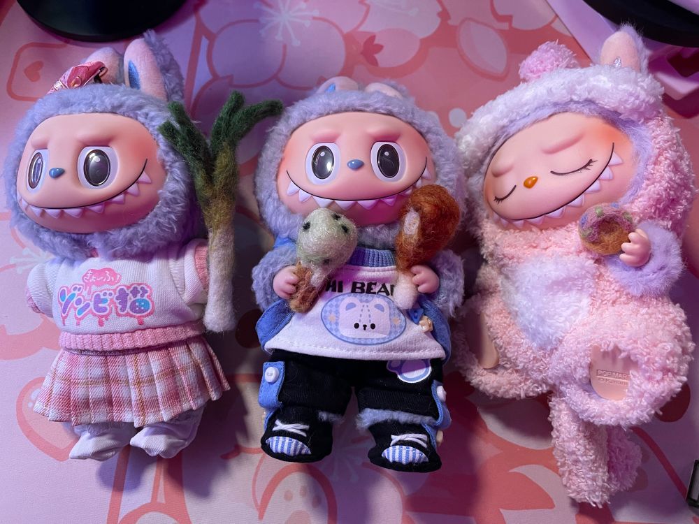 Three cute Labubu all dressed up holding needle felted leek, mint chip ice cream cone, fried chicken drumstick, and sprinkle donut.