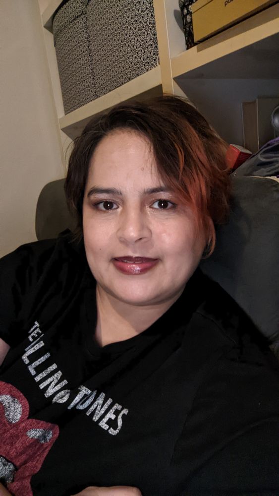 Selfie de Shérazade elle porte un t-shirt noir Rolling Stones et esquisse un début de sourire