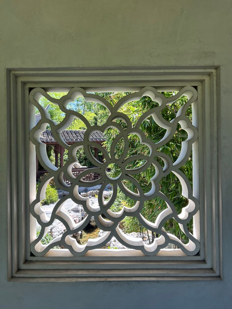 Photo looking through window that has been carved into a flower. 