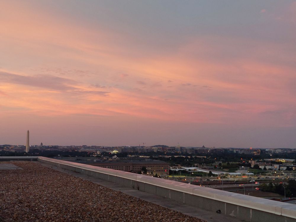 An orange sunset from an apartment building roof. In the distance are the US Capitol, Jefferson Memorial, and Washington Monument 